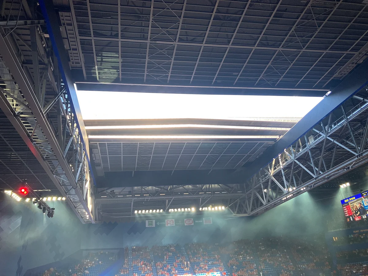 Inside RAC Arena with the roof open and haze over the crowd