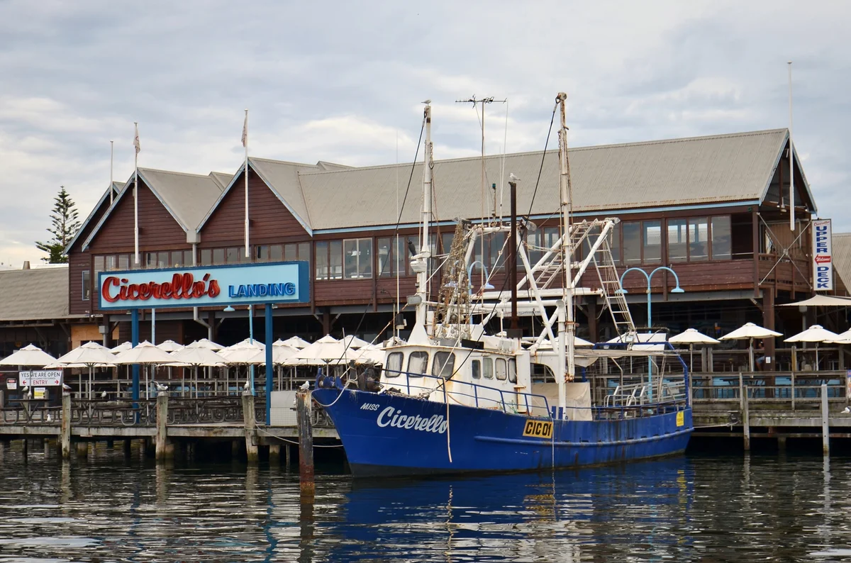Cicerello's Landing seen from the water, with a blue fishing boat moored in front