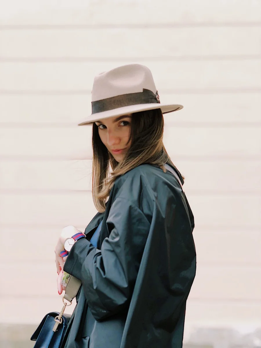 A woman in a pale wide-brimmed hat and a dark green coat