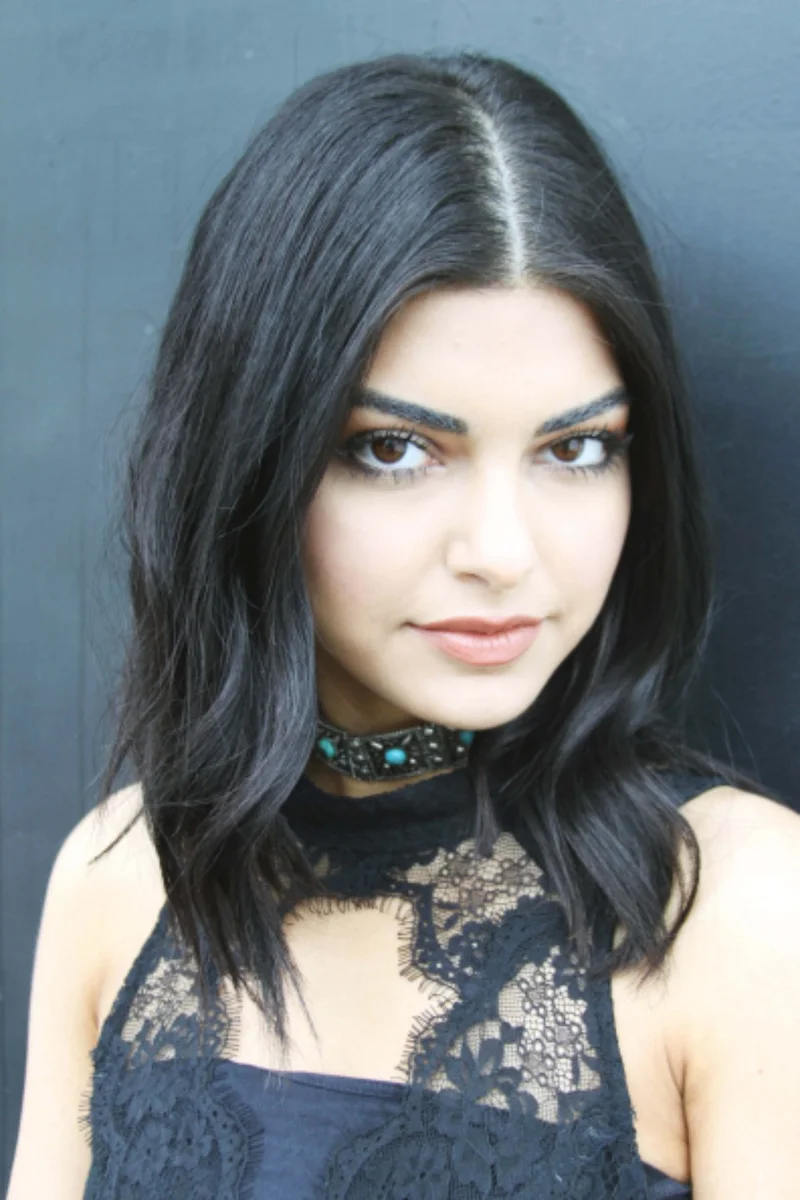 A woman with dark hair wearing a black lace top and a jewelled choker