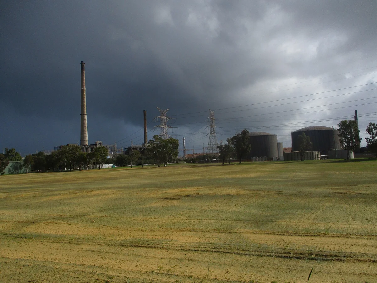 Kwinana Power Station chimney and tanks under a dark storm sky