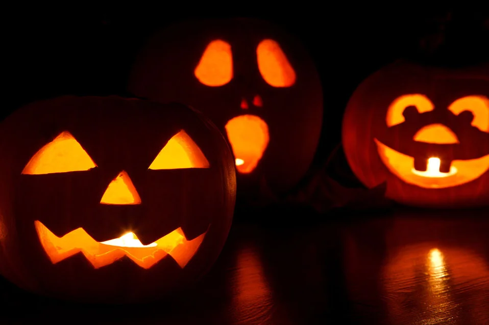 Three carved jack-o'-lanterns glowing in the dark